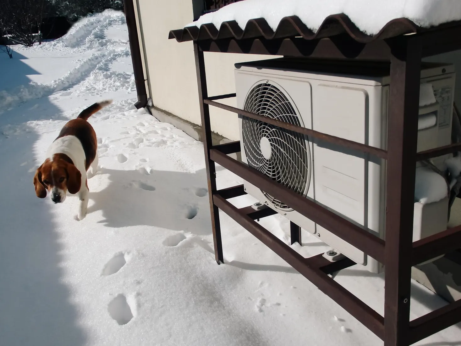 Pompe à chaleur aérothermique fonctionnant en hiver devant une maison