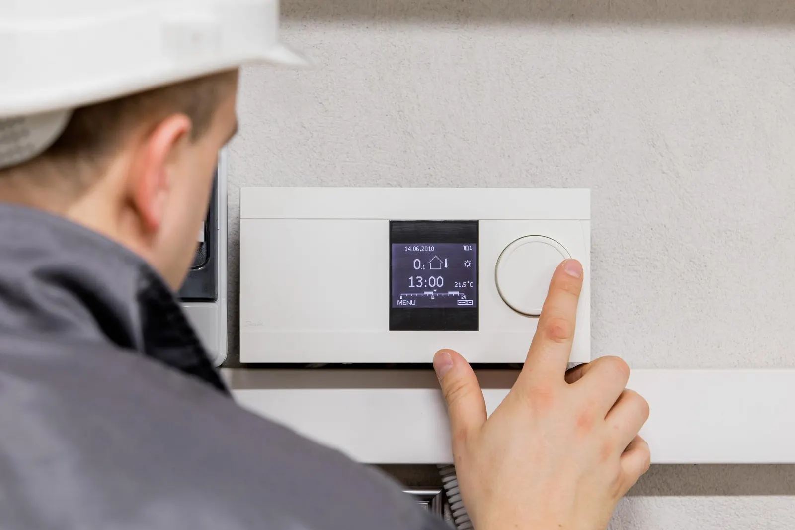 Ingénieur ajustant un thermostat pour un chauffage automatisé efficace